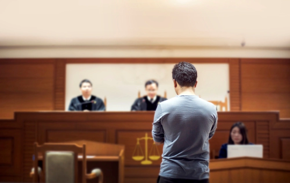 A picture of a person in a courtroom with a judge and a jury