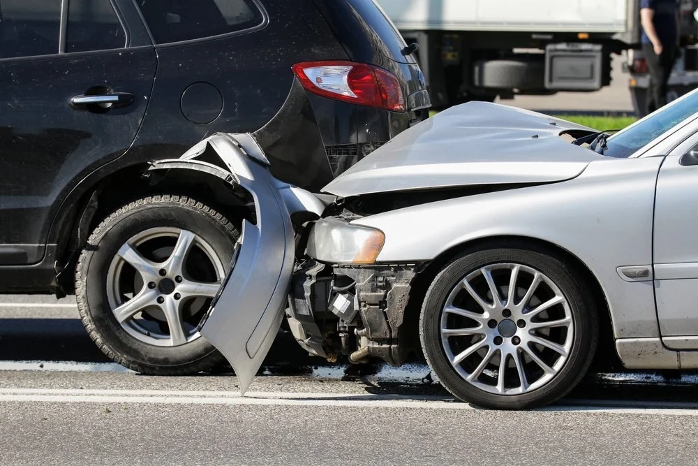 A car accident scene with a police officer and an ambulance in the background