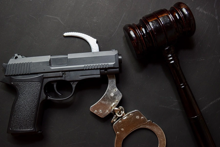 Handcuffs, a firearm, and a gavel laid out, representing the serious implications of robbery with a deadly weapon.