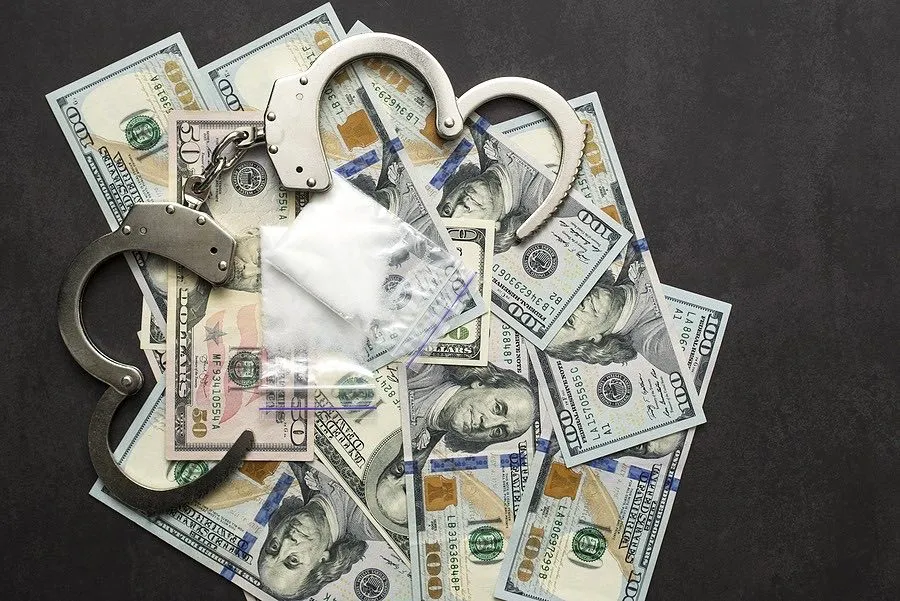 Drugs, handcuffs, and cash symbolizing the need for a Fort Pierce drug crime lawyer.