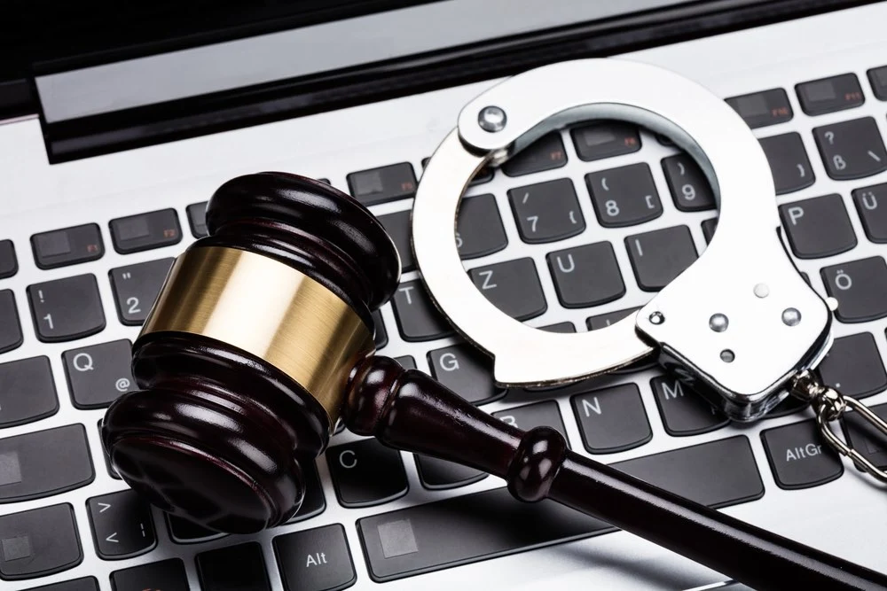 A laptop, gavel, and handcuffs, symbolizing the severe consequences of child pornography charges.