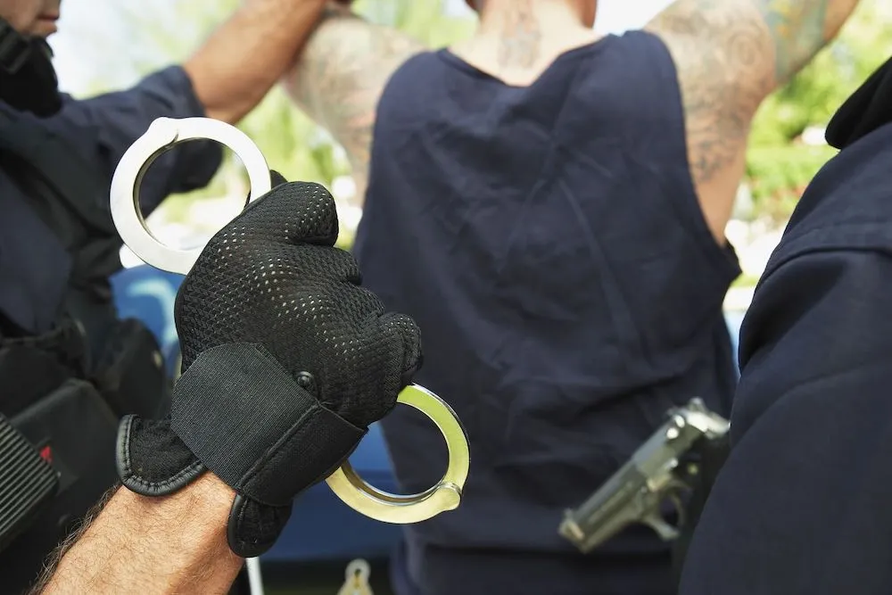 A young person being arrested in handcuffs, highlighting the critical importance of promptly hiring a juvenile crime defense lawyer