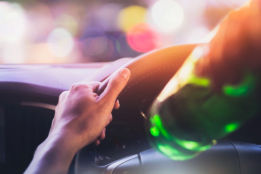 A person drinking an alcoholic beverage while driving, underscoring the importance of hiring a third DUI defense lawyer in Stuart, FL if facing charges